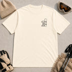 Natural tee featuring minimalist black line art of snowboard goggles, a snowboard boot, and an upright snowboard on the left chest.