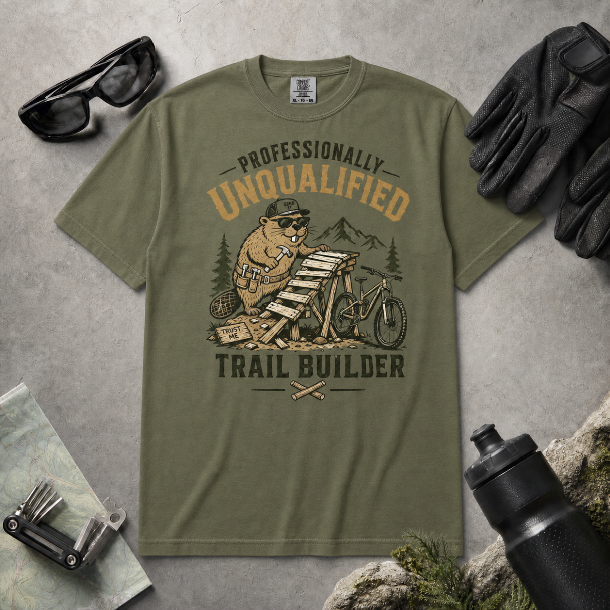 Hemp green t-shirt with beaver graphic and text on a gray surface with accessories.