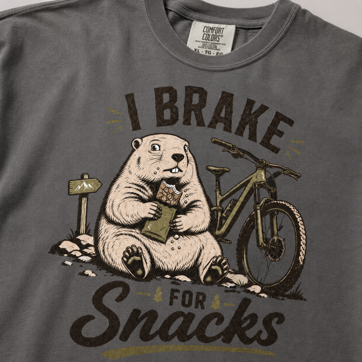 Close-up of a pepper gray t-shirt with a funny “I Brake for Snacks” graphic showing a snack-loving marmot resting beside a mountain bike.