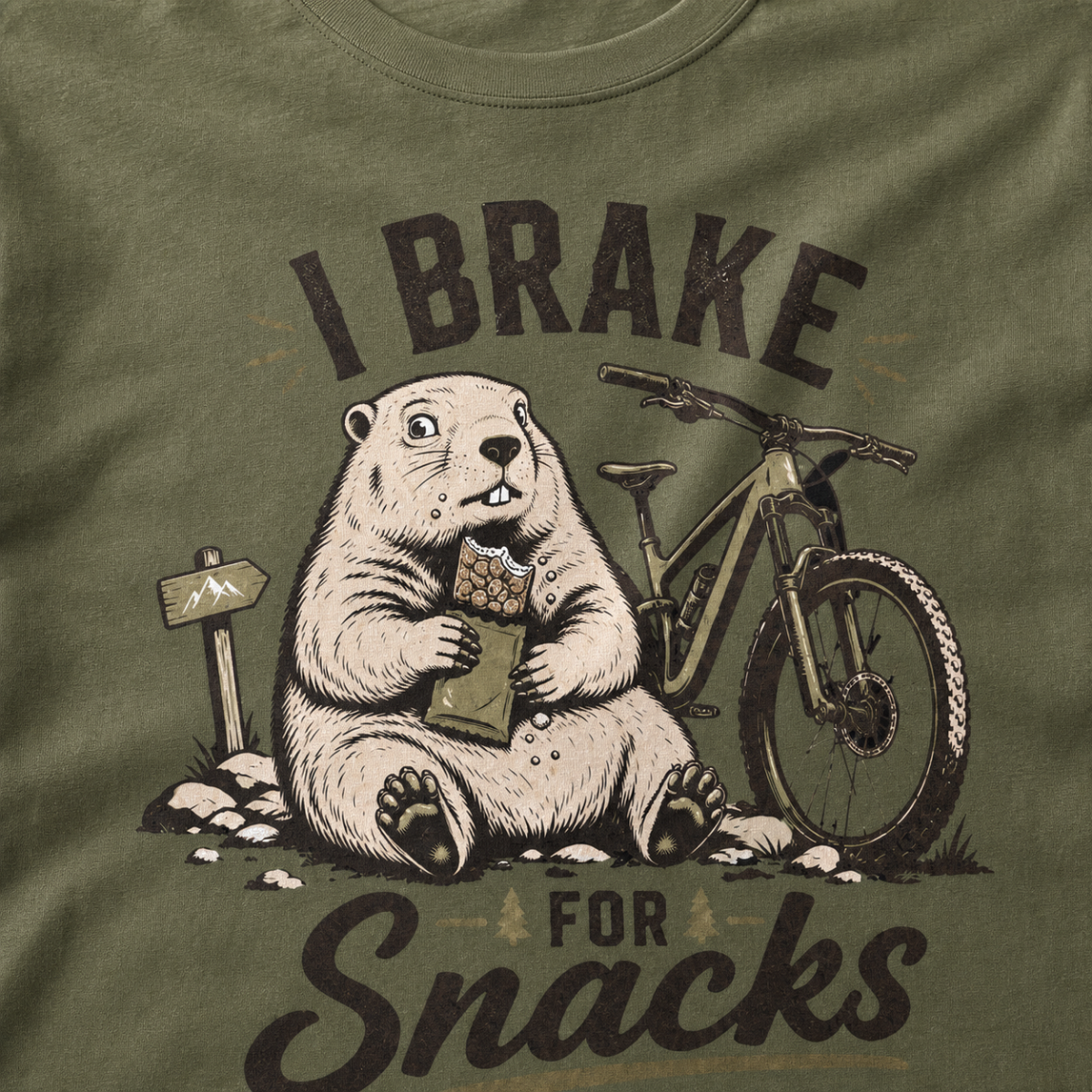Close-up of a hemp green t-shirt with a funny “I Brake for Snacks” graphic showing a snack-loving marmot resting beside a mountain bike.
