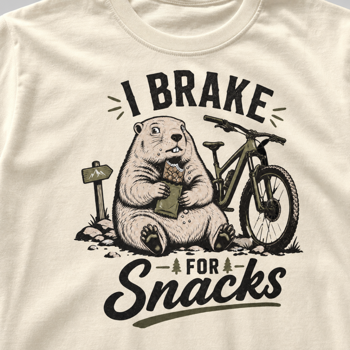 Close-up of an ivory white t-shirt with a funny “I Brake for Snacks” graphic showing a snack-loving marmot resting beside a mountain bike.