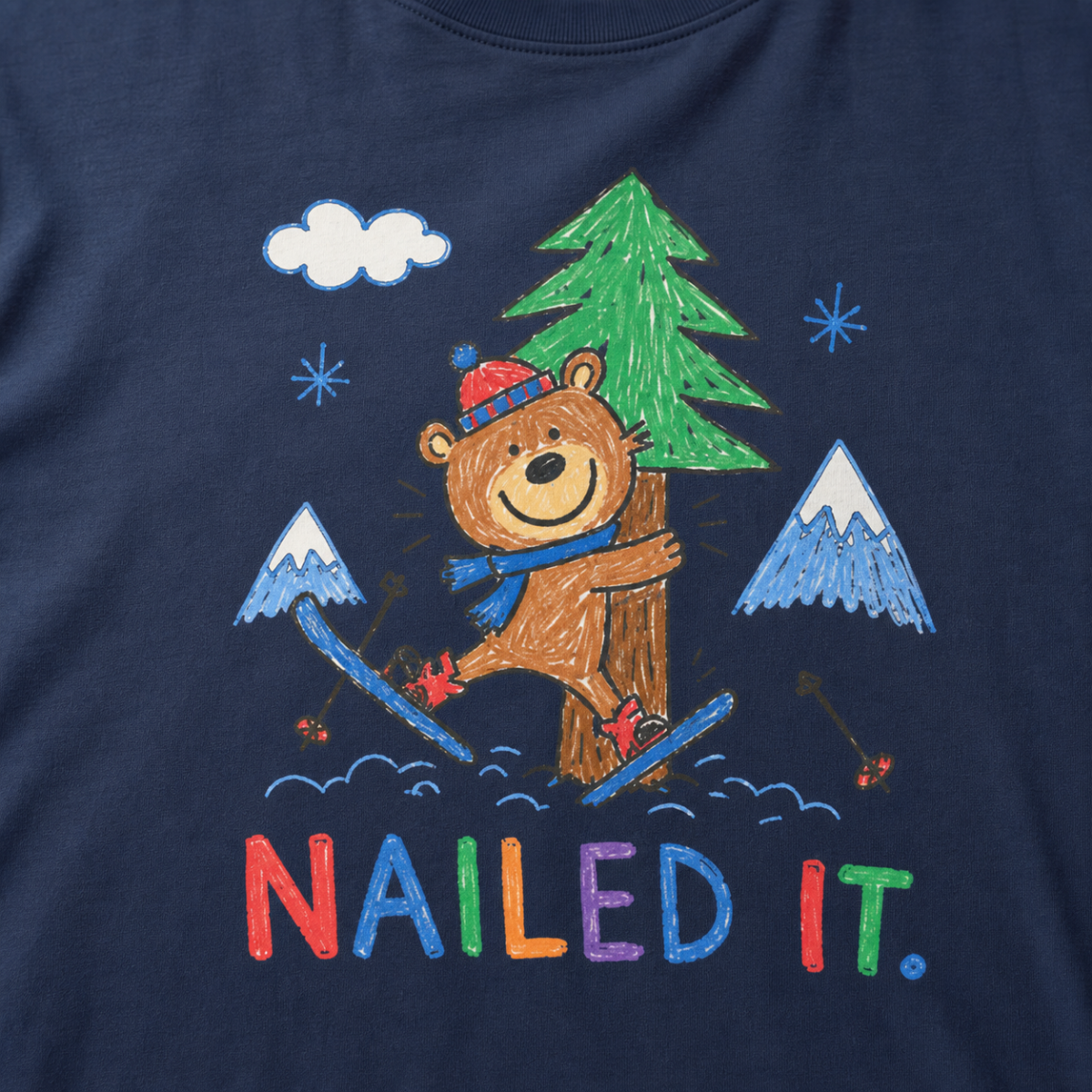 Close-up of a navy blue t-shirt with a childlike crayon-style ski design showing a smiling bear hugging a tree, with colorful “Nailed It.” text.