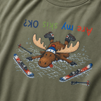 Close-up of a moss green t-shirt showing a crashed moose lying upside down in the snow with loose ski gear and colorful “Are My Skis OK?” text.