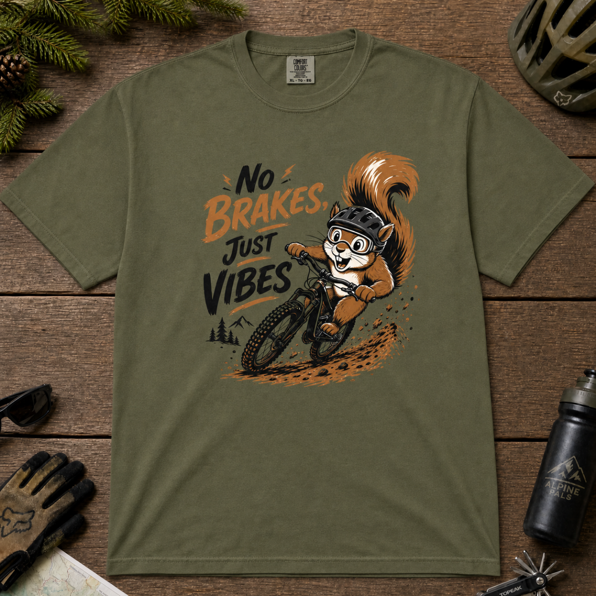 Hemp green t-shirt featuring a squirrel mountain biking down a dirt trail with bold “No Brakes, Just Vibes” lettering.