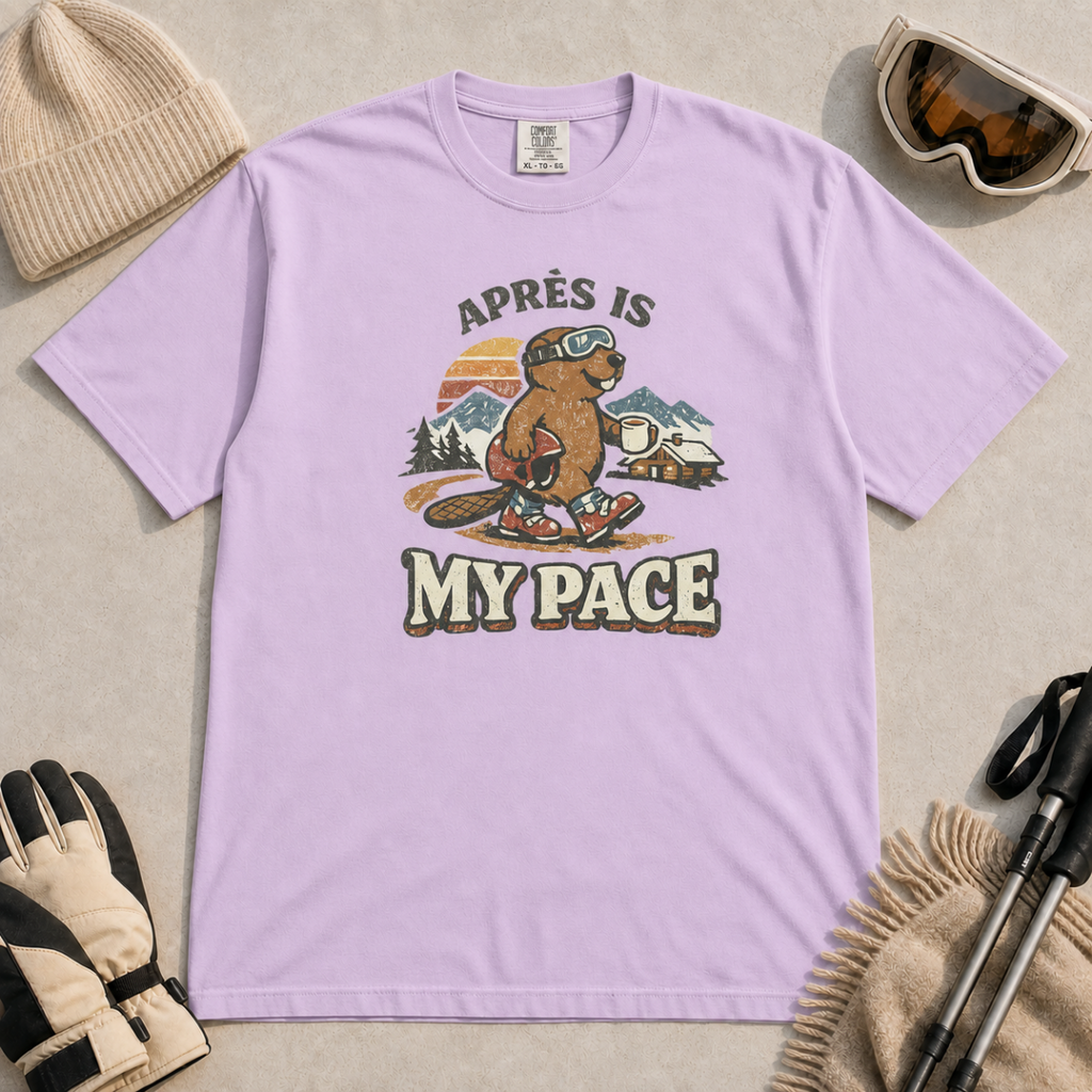 Orchid t-shirt featuring an “Après Is My Pace” design with a beaver wearing ski goggles and boots, carrying a helmet and hot drink against a retro mountain and chalet scene.