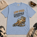 Washed Denim t-shirt featuring a vintage sloth wearing ski goggles and relaxing in a rocking chair with a hot drink, with the phrase “Low-Speed Lifestyle.”