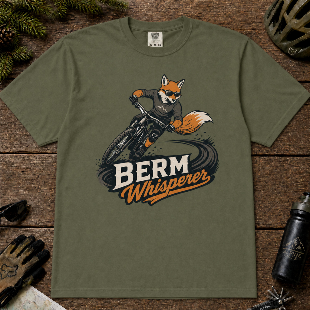 Moss t-shirt featuring an orange fox mountain biker leaning aggressively through a dirt berm above the bold “Berm Whisperer” design.
