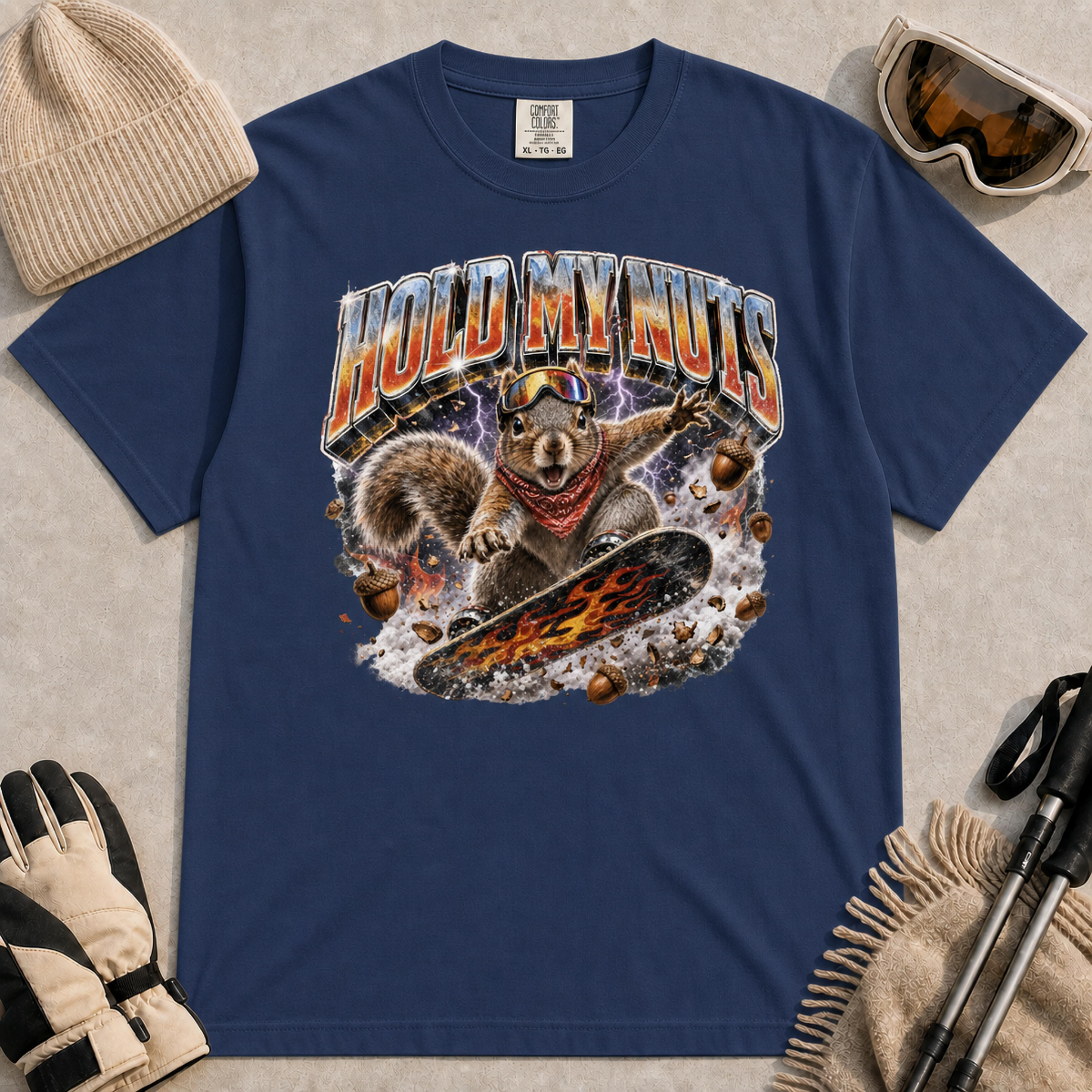 Navy tee featuring a retro “Hold My Nuts” snowboarding squirrel graphic with flying acorns, lightning, and bold metallic lettering.