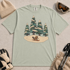 Bay t-shirt featuring a whimsical winter illustration of a small beaver snowboarding across a snowy clearing beneath four snow-covered evergreen trees.