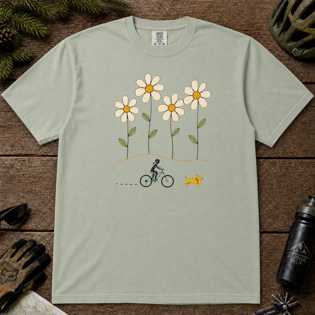 Bay Comfort Colors tee featuring four oversized daisies above a female mountain biker riding alongside a small yellow dog.