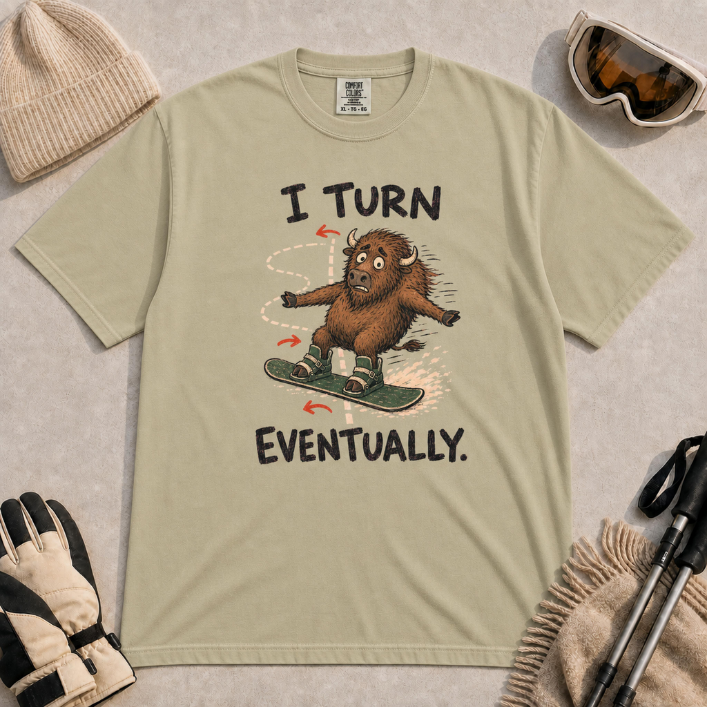 Khaki t-shirt featuring a childlike hand-drawn bison snowboarding along a winding path, with the phrase “I Turn Eventually.”