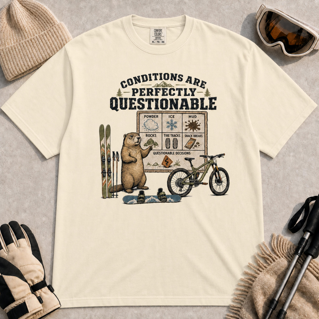 Ivory tee featuring a marmot presenting a questionable conditions chart beside skis, a snowboard and a mountain bike, with “Conditions Are Perfectly Questionable” text.
