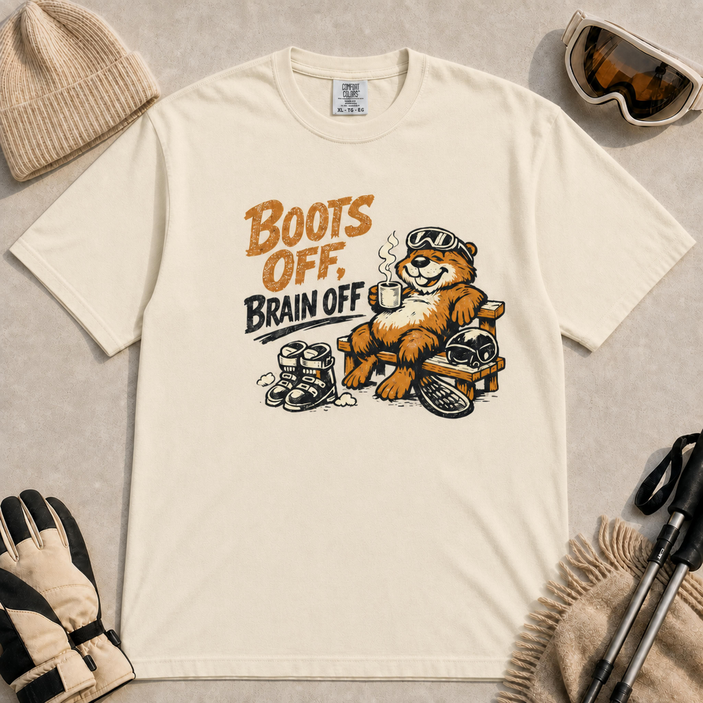 Ivory t-shirt featuring a laid-back beaver  enjoying a hot drink beside ski boots, a helmet and snowboard with the phrase “Boots Off, Brain Off.”
