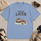 Washed denim t-shirt featuring a relaxed red panda lying in the snow beside a snowboard, wearing ski goggles beneath the phrase “Maybe Later.”