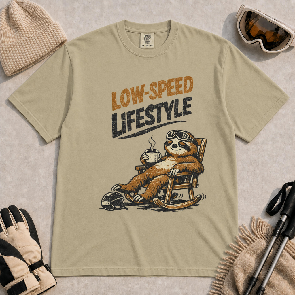 Khaki t-shirt featuring a vintage sloth wearing ski goggles and relaxing in a rocking chair with a hot drink, with the phrase “Low-Speed Lifestyle.”