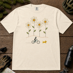 Ivory Comfort Colors tee featuring four oversized daisies above a female mountain biker riding alongside a small yellow dog.