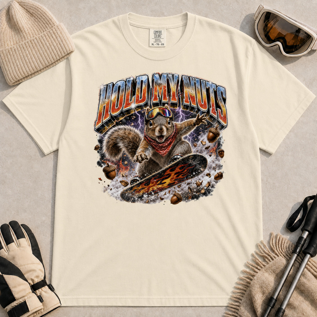Ivory tee featuring a retro “Hold My Nuts” snowboarding squirrel graphic with flying acorns, lightning, and bold metallic lettering.