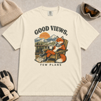 Ivory tee featuring a relaxed fox lounging in a wooden chair with ski goggles and a mug, framed by mountain scenery and the phrase “Good Views, Few Plans.”