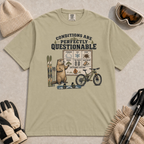 Khaki tee featuring a marmot presenting a questionable conditions chart beside skis, a snowboard and a mountain bike, with “Conditions Are Perfectly Questionable” text.