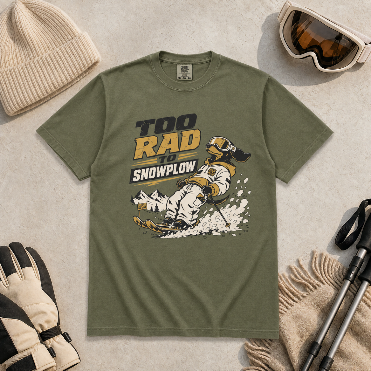 Hemp green t-shirt with snow-related graphic and text, surrounded by winter accessories on a light background