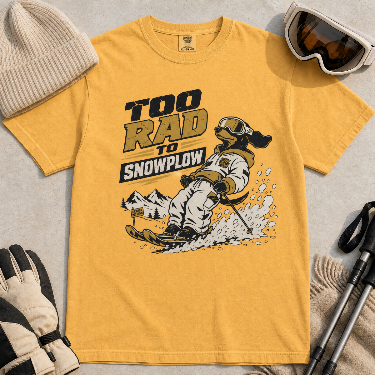 Mustard yellow t-shirt with a graphic of a dachshund snowplowing and text 'Too Rad to Snowplow' on a plain background.