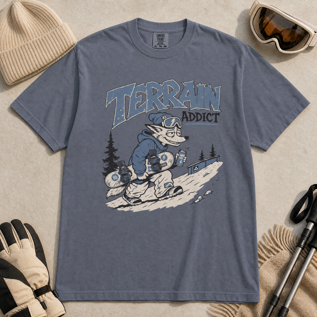 Denim colored t-shirt with 'Terrain Addict' graphic on a light gray surface with winter accessories.