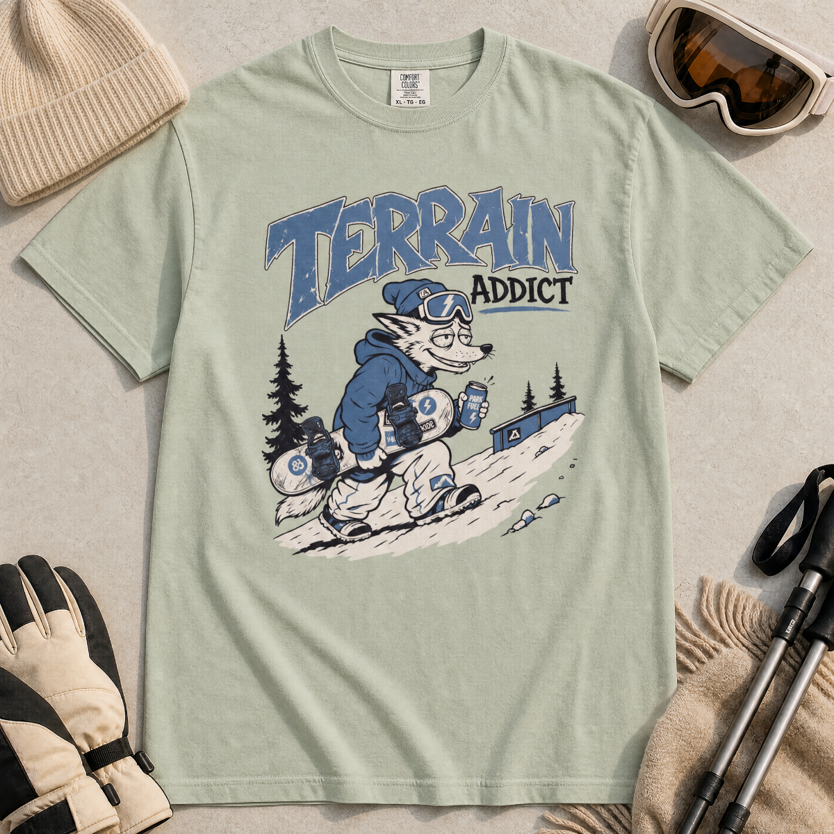 Bay green t-shirt with 'Terrain Addict' graphic on a light gray surface with winter accessories.