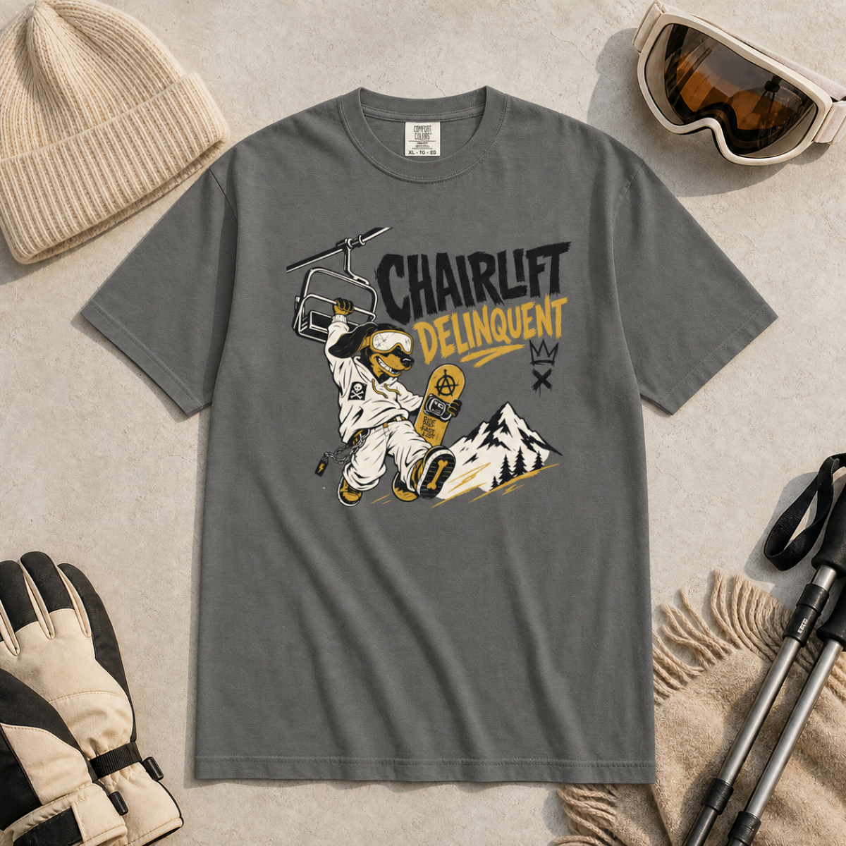Pepper gray t-shirt with a graphic design featuring an astronaut and text, surrounded by winter gear on a light background.