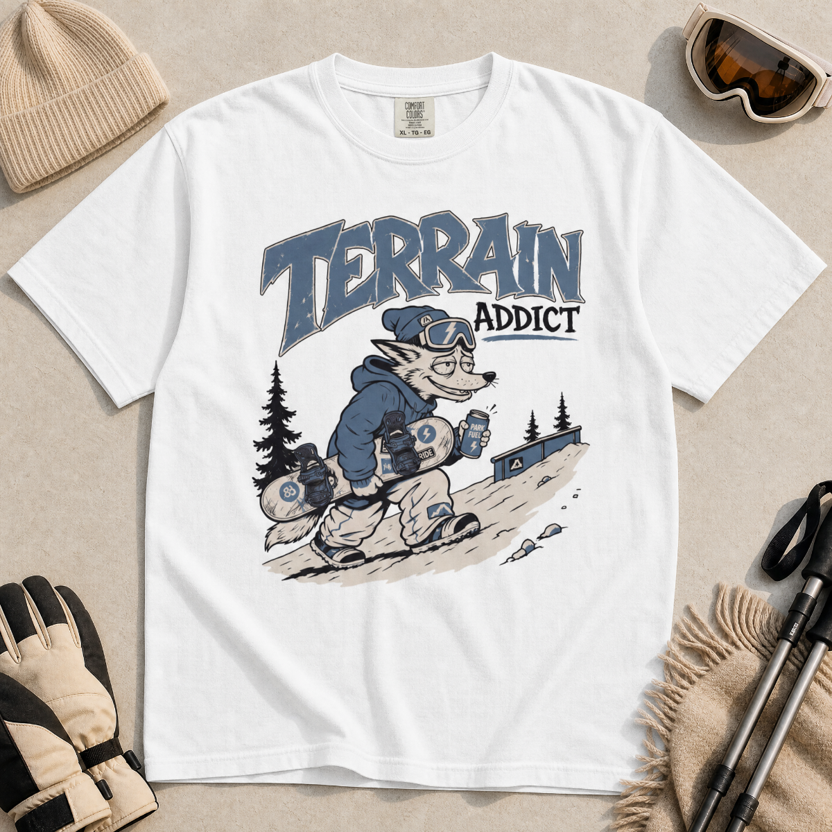 White t-shirt with 'Terrain Addict' graphic on a light gray surface with winter accessories.