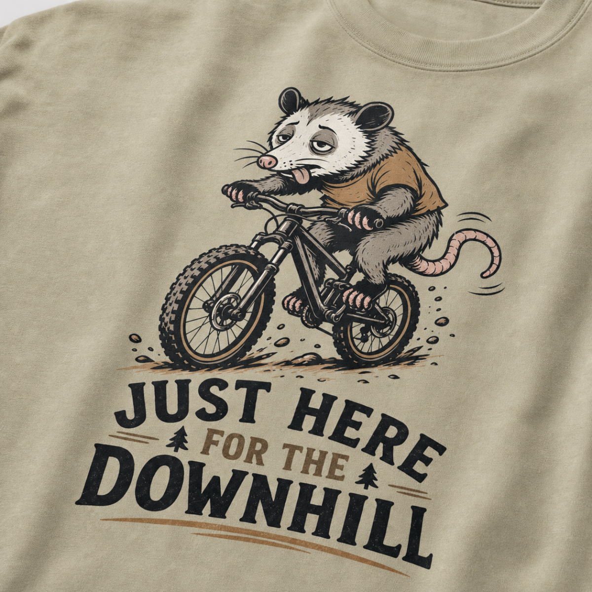 Khaki colored t-shirt with an opossum riding a bike graphic and text 'Just Here for the Downhill'.