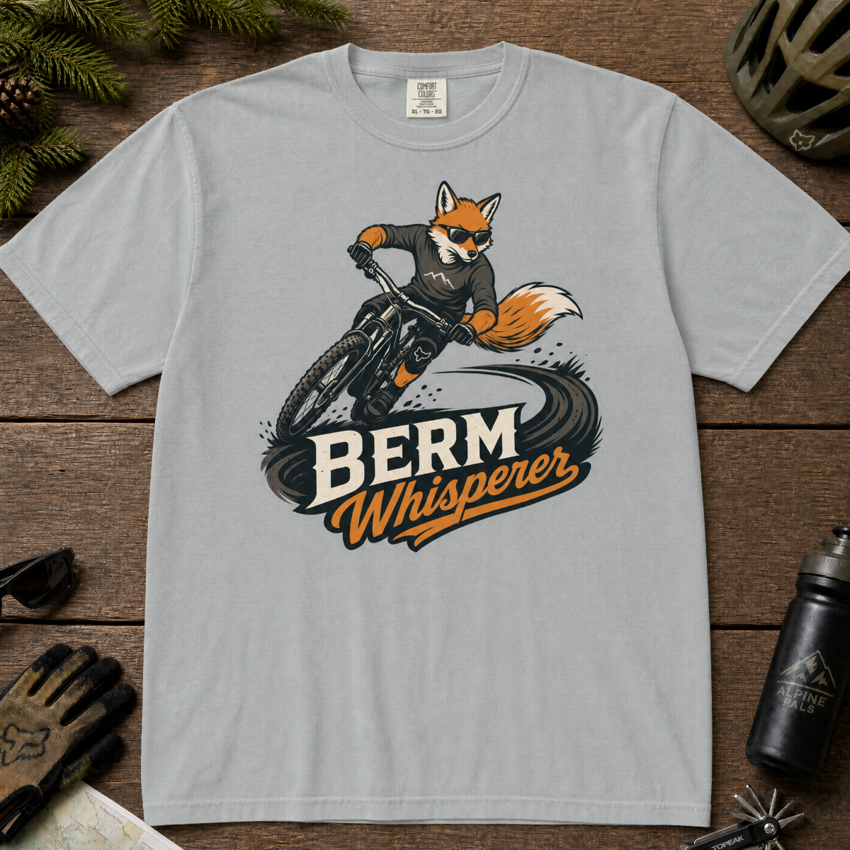 Granite gray t-shirt with a graphic of a fox riding a bike and ' Berm Whisperer'.