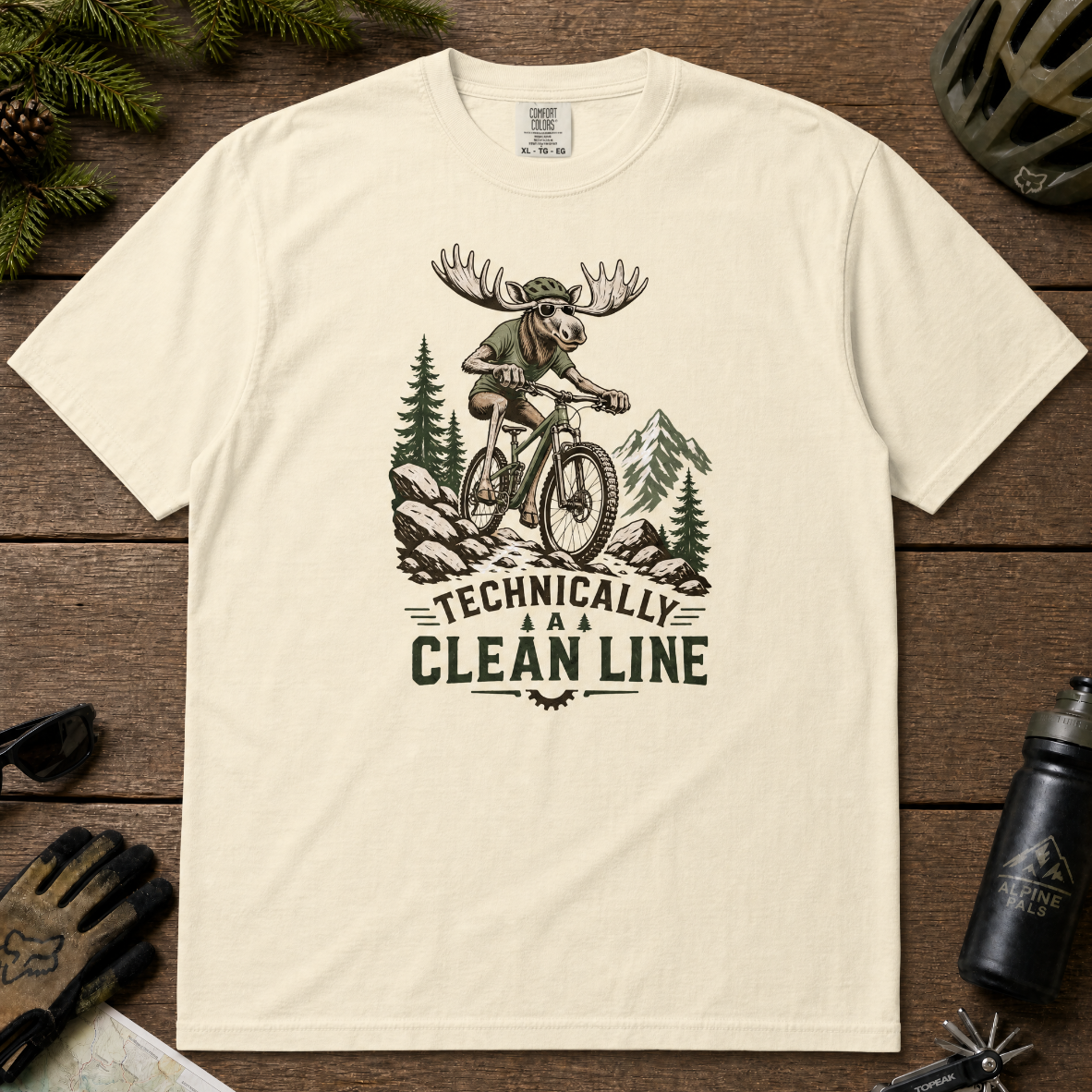 Ivory white t-shirt with a graphic of a moose riding a bike and text 'Technically A Clean Line'.