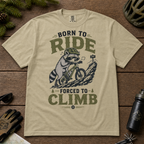 Khaki colored t-shirt with a graphic of a raccoon riding a bike and text 'Born to Ride, Forced to Climb'.