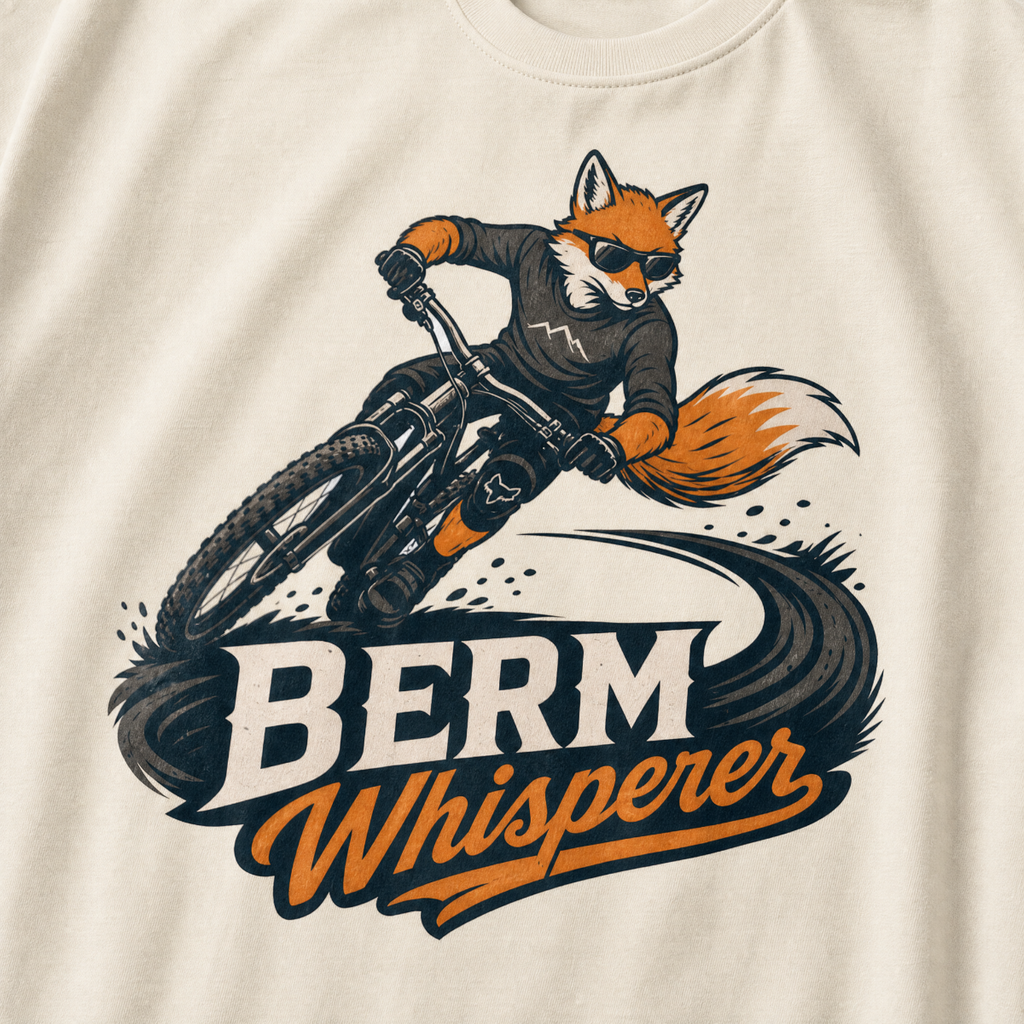 Ivory white t-shirt with a graphic of a fox riding a bike and ' Berm Whisperer'.