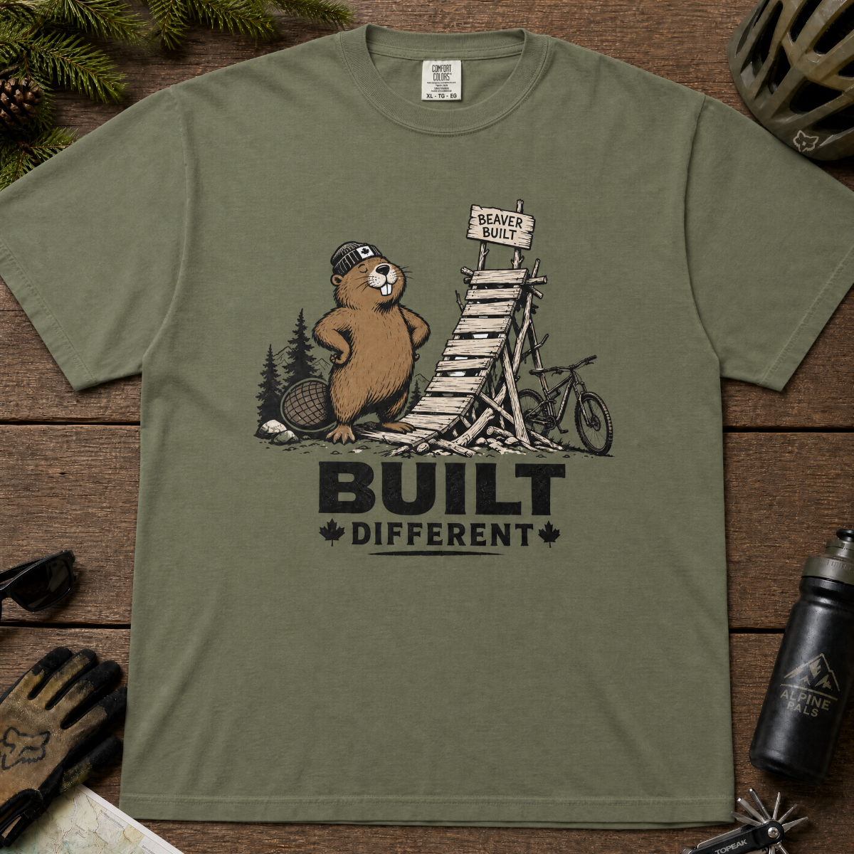 Moss green t-shirt with beaver graphic and 'Built Different' text on a white background