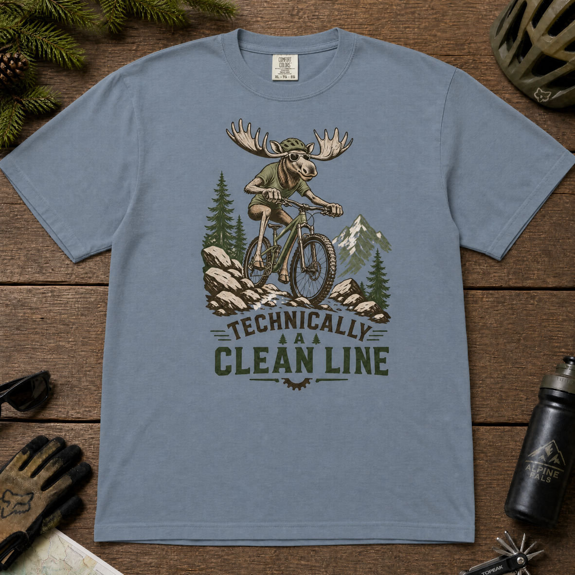 Blue jean colored t-shirt with a graphic of a moose riding a bike and text 'Technically A Clean Line'.