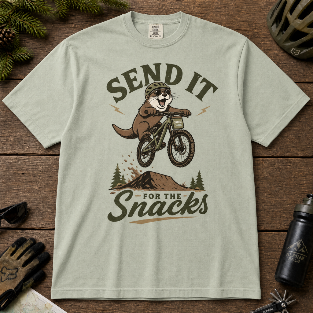 Bay green t-shirt with an otter riding a bike graphic and text 'Send it for the snacks'.