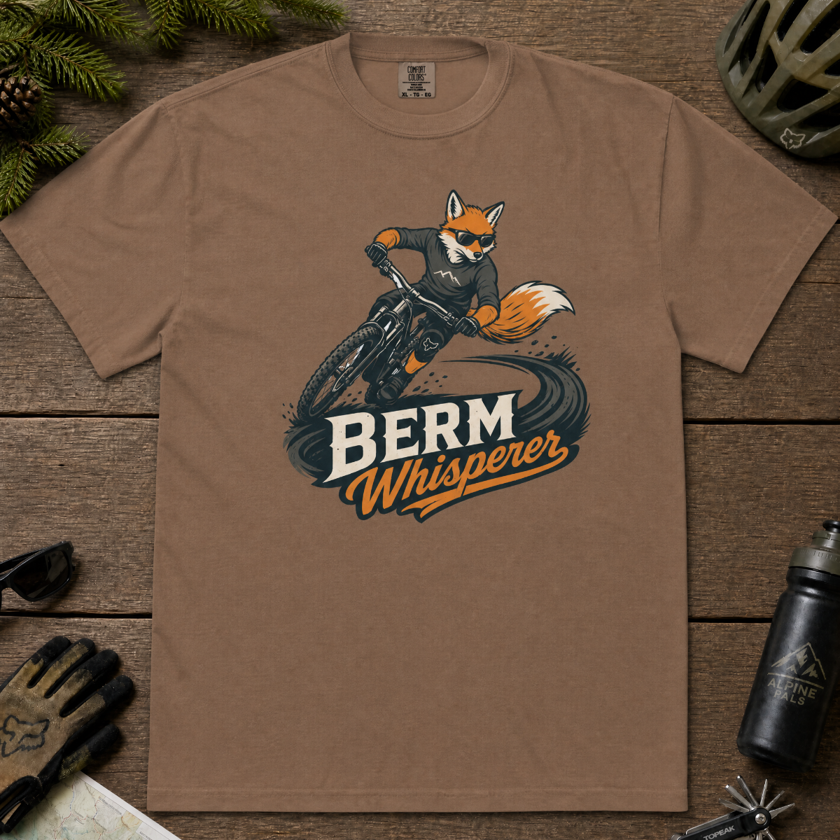 Espresso brown t-shirt with a graphic of a fox riding a bike and ' Berm Whisperer'.
