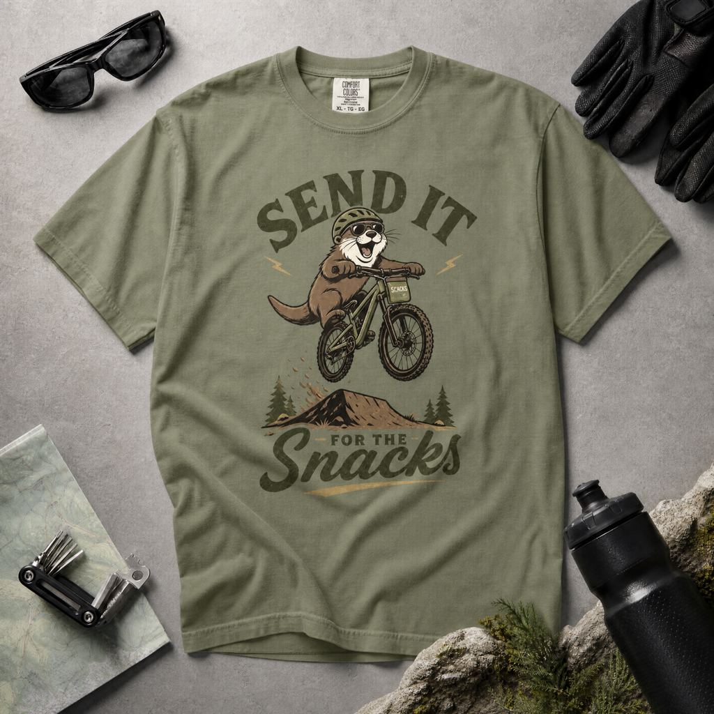 Moss green t-shirt with a graphic of an otter on a bike and text 'Send it for the snacks'.