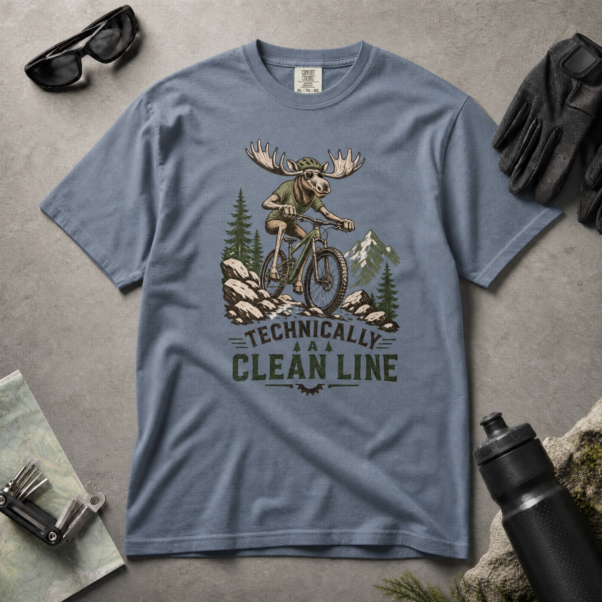 Blue jean colored t-shirt with a graphic of a moose riding a bike and text 'Technically A Clean Line' on a light gray background.