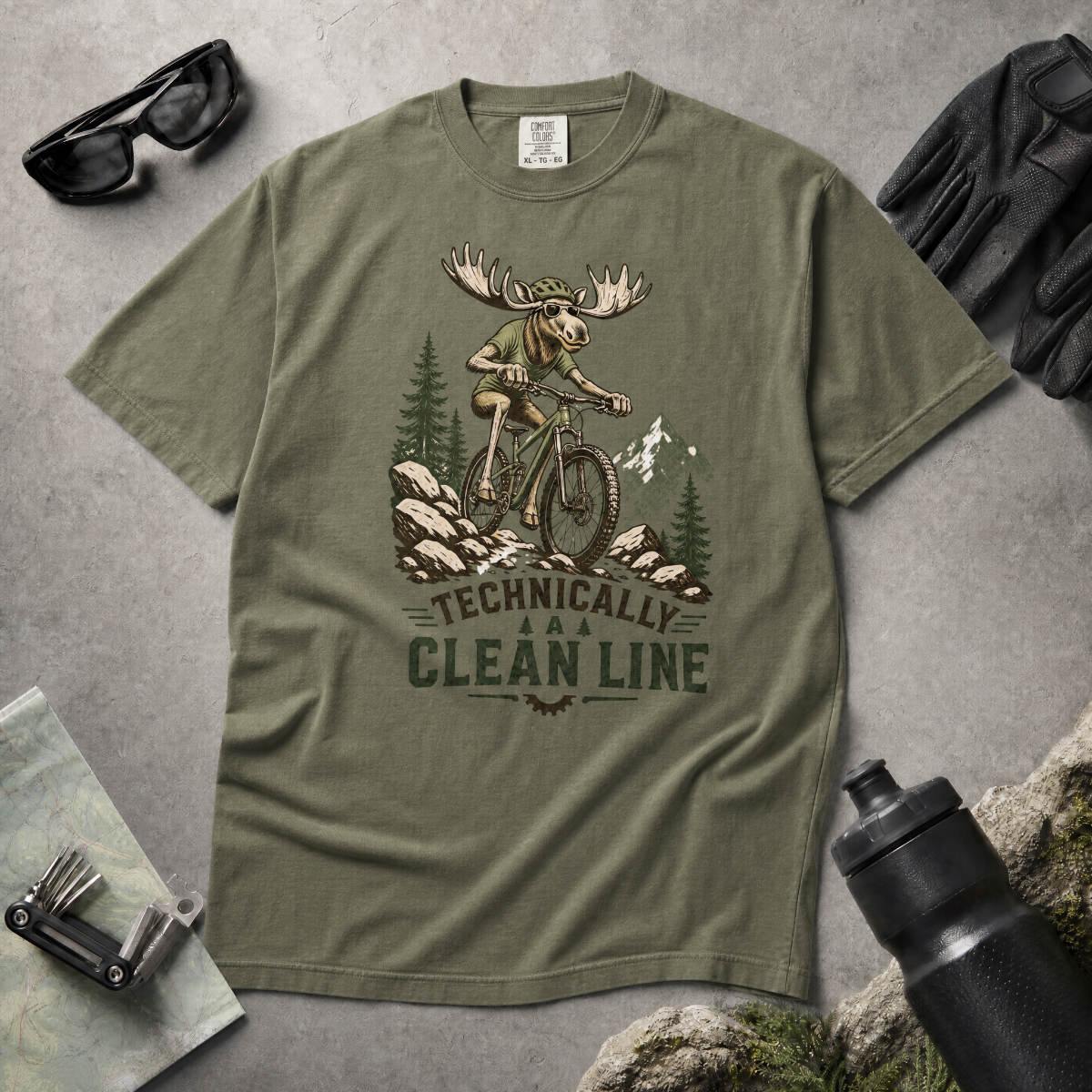 Moss green t-shirt with a moose riding a bike graphic and 'Technically a Clean Line' text on a light gray background.