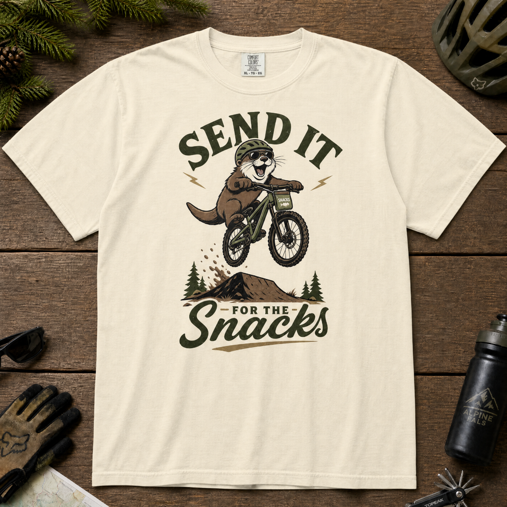 Ivory white t-shirt with graphic of an otter on a bike and text 'Send it for the snacks'.