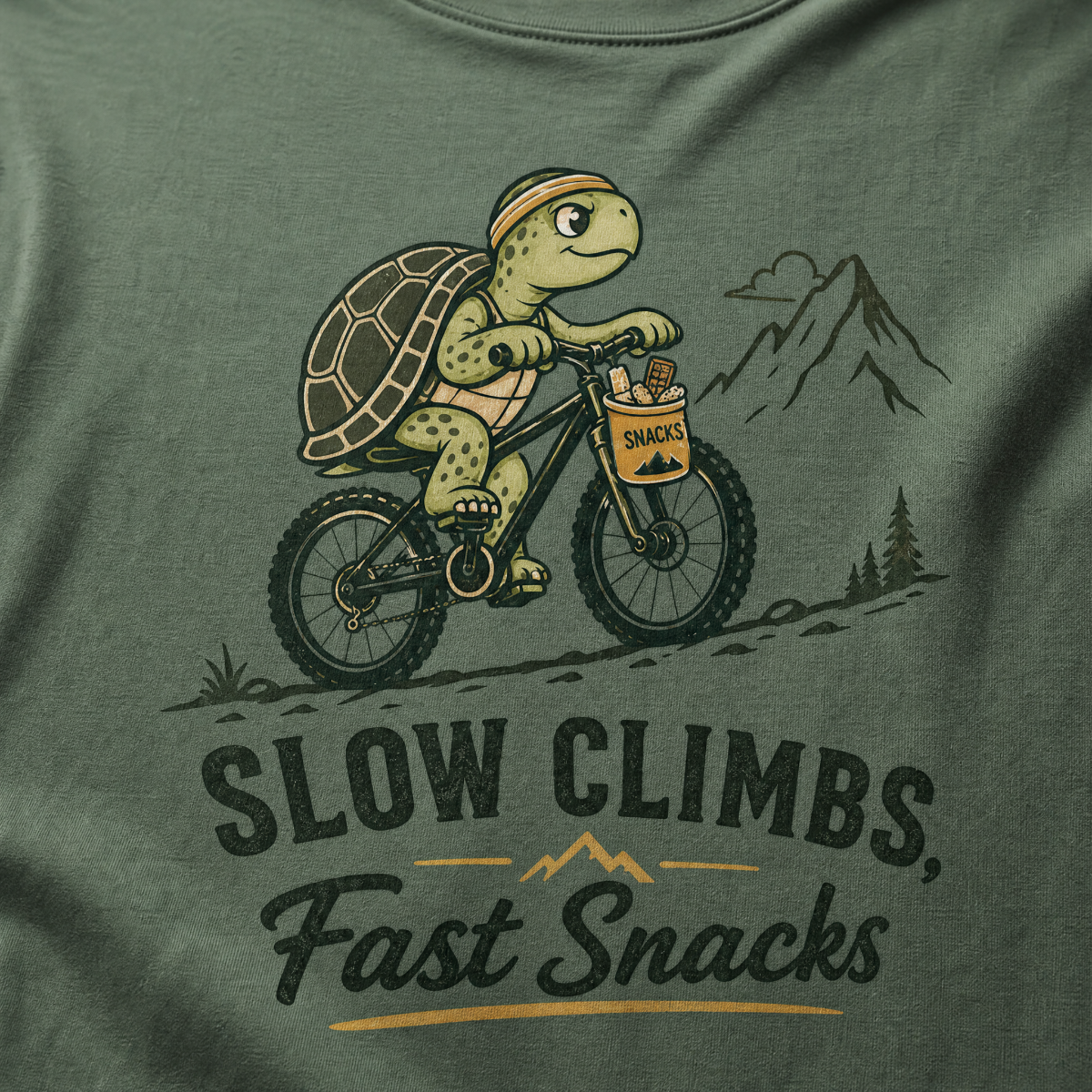 Blue spruce colored t-shirt with a graphic of a turtle riding a bike and text 'Slow Climbs, Fast Snacks'.