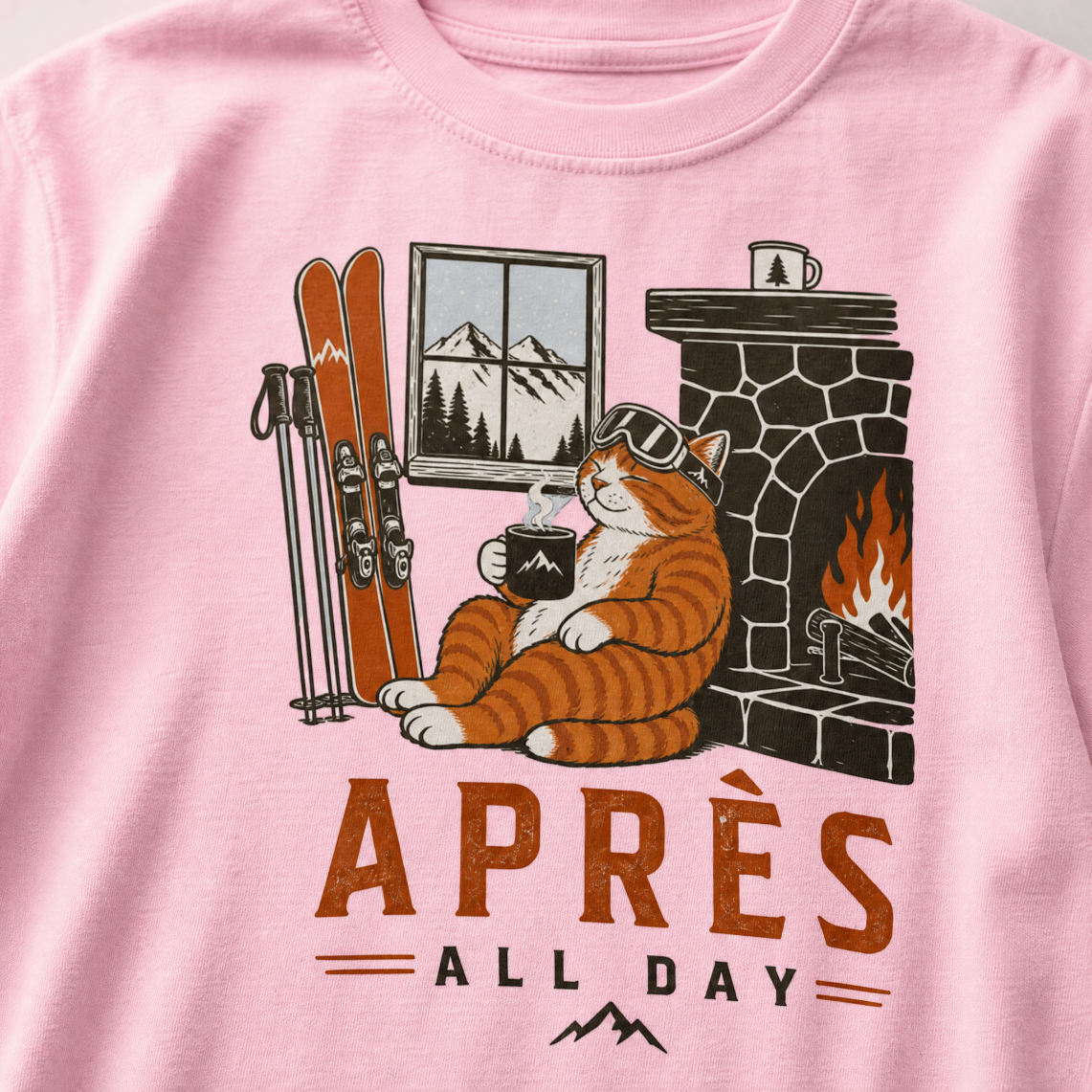 Blossom pink t-shirt with a graphic of a cat by a fireplace and skis, with 'Après All Day' text.