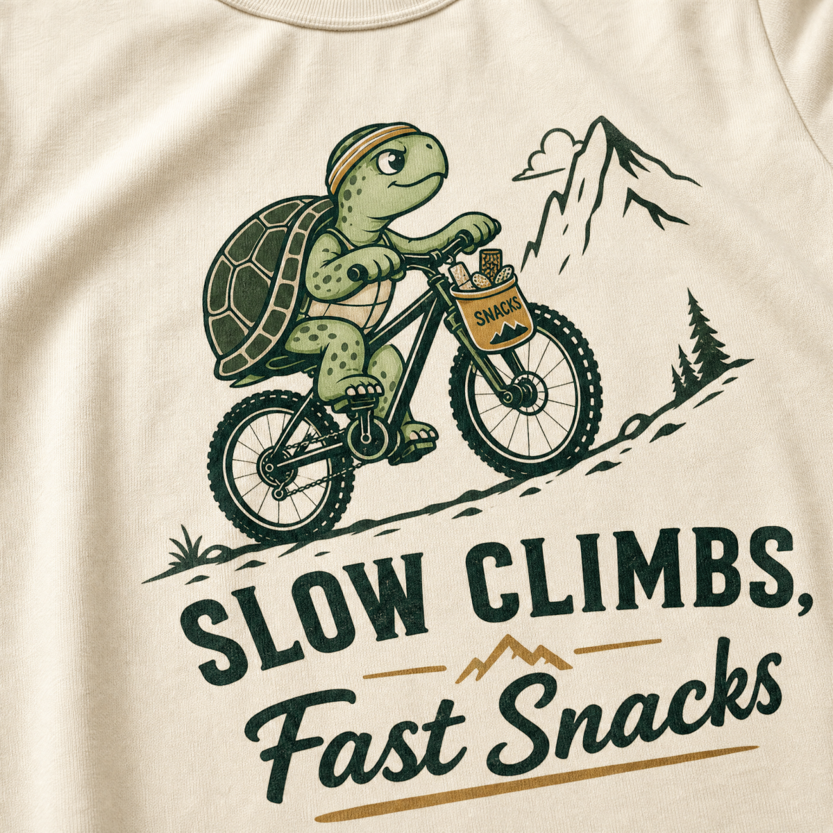 Ivory white t-shirt with a graphic of a turtle riding a bike and text 'Slow Climbs, Fast Snacks'.