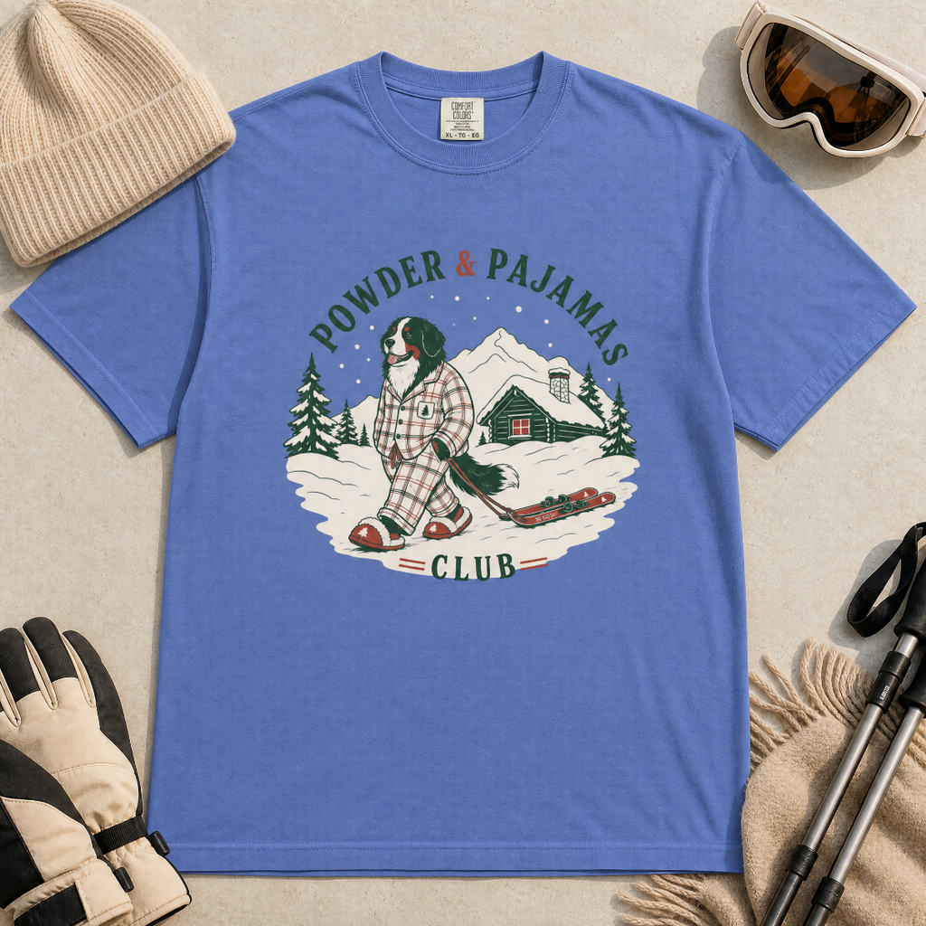 Mystic blue t-shirt with a graphic of a dog in checkered pajamas pulling skis, trees, and a cabin, with 'Powder & Pajamas Club' text.