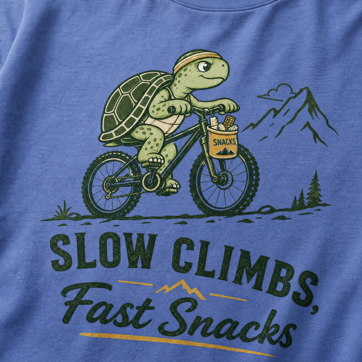 Mystic blue colored t-shirt with a graphic of a turtle riding a bike and text 'Slow Climbs, Fast Snacks'.