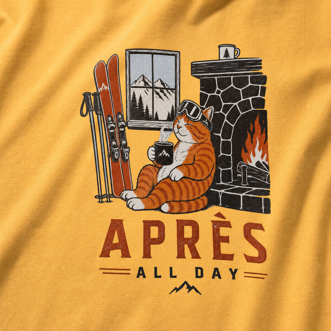 Mustard yellow t-shirt with a graphic of a cat by a fireplace and skis, with 'Après All Day' text.