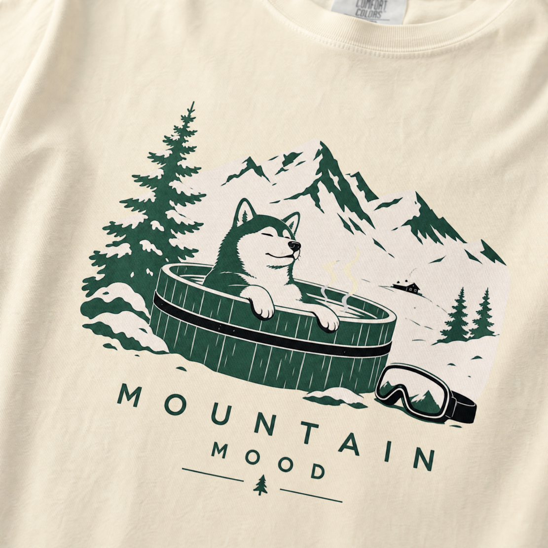 Ivory white t-shirt with a graphic of a husky in a hot tub surrounded by mountains and trees.