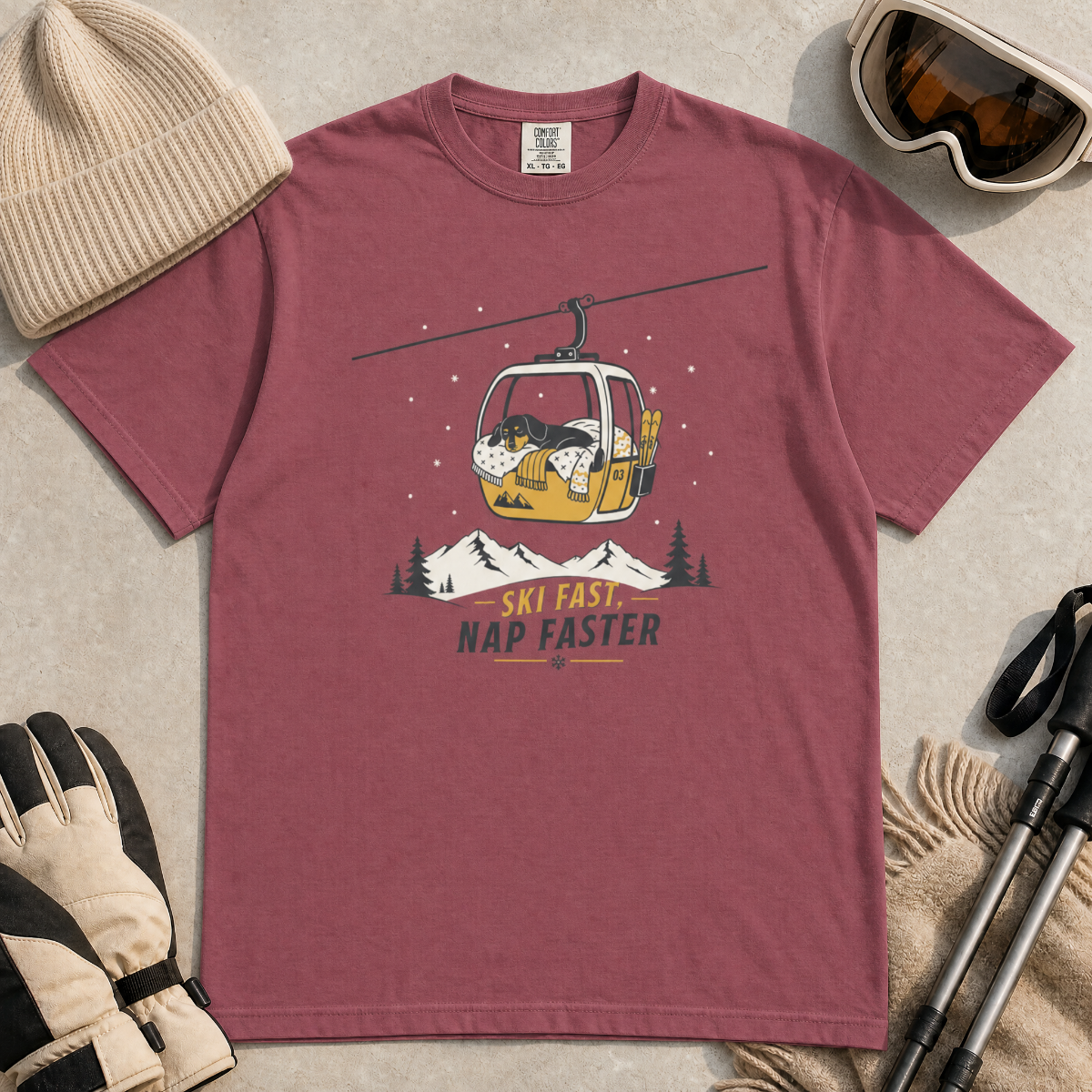 Brick red t-shirt with a graphic of a dog in a gondola lift and text 'Ski Fast Nap Faster'.